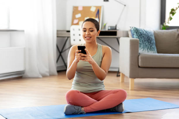 istock woman with smartphone sits on exercise mat at home 1304854485