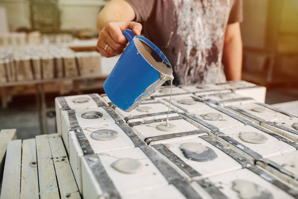 Man pouring liquid clay in molds for casting cups and other tableware stock photo