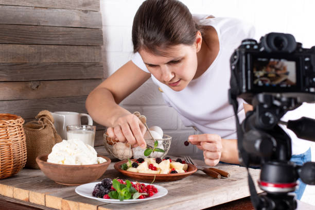 Professional food blogger taking pictures of pastry on table with camera. Female photographer taking pictures of sweet food, camera mounted on tripod Professional food blogger taking pictures of pastry on table with dslr camera. Female photographer taking pictures of sweet food, camera mounted on tripod behind the scenes photos stock pictures, royalty-free photos & images