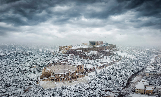The Parthenon Temple and the Herodion Theater at the Acropolis of Athens, Greece, with ice and snow during a winter snowstorm
