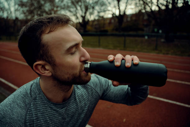 istock Caucasian male athlete standing on tracking field drinking watr from bottle 1304857323