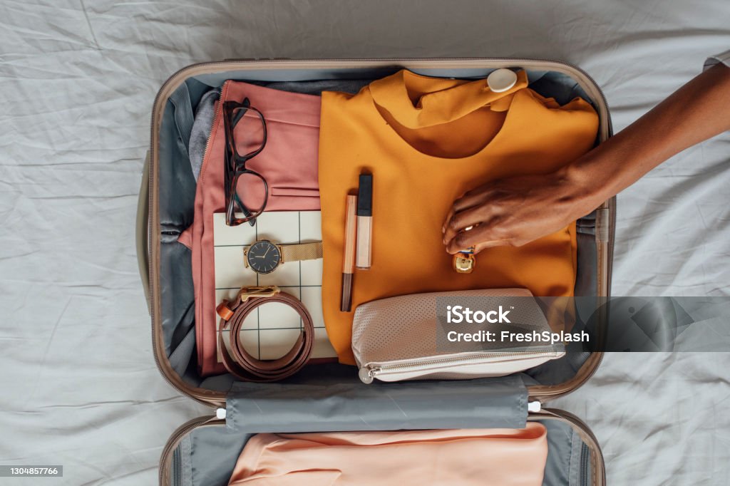 A Woman Packing her Clothes in a Suitcase Hands of unrecognisable woman putting stuffs in her suitcase. Suitcase Stock Photo