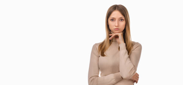 istock Pensive blond girl with thoughtful expression, keeps hand on chin, plans something or makes choice. Place for ad 1304858487