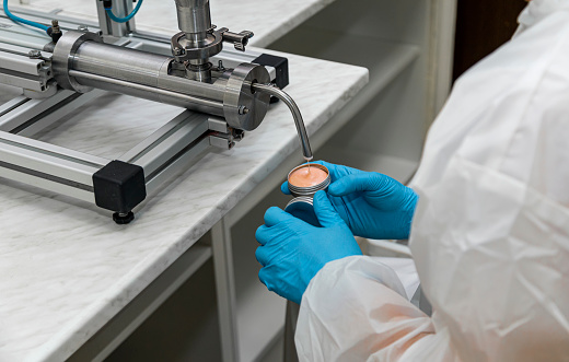 Close up of human hands working at cosmetic factory, medical products