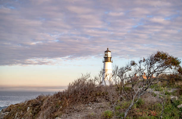 phare de travail au-dessus d’une falaise touffie contre un ciel nuageux sur la côte atlantique dans le maine de portland en nouvelle-angleterre - travel maine coast region lighthouse lighting equipment photos et images de collection