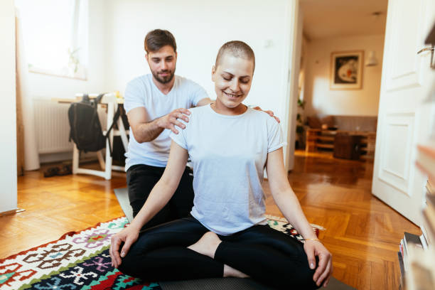 pareja en casa haciendo yoga en casa - mujer curada de cáncer y su marido hacen ejercicio juntos - stretching boyfriend indoors lifestyles fotografías e imágenes de stock