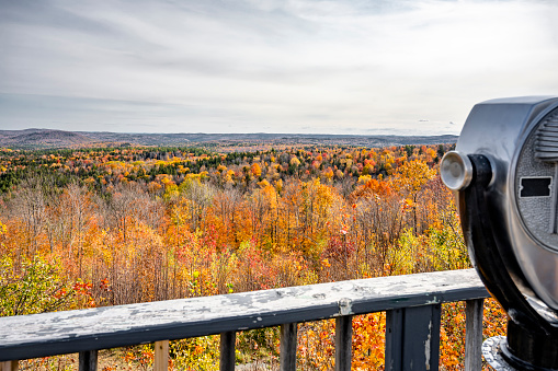 Viewpoint with Coin Binoculars of mesmerizing colorful atmospheric landscape with an autumn maple trees on the hills of the mountain ridge attract tourists and travelers to visit Vermont New England