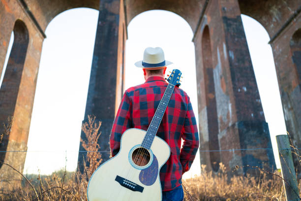 istock Man wandering in nature at sunset with guitar on his back 1304869993