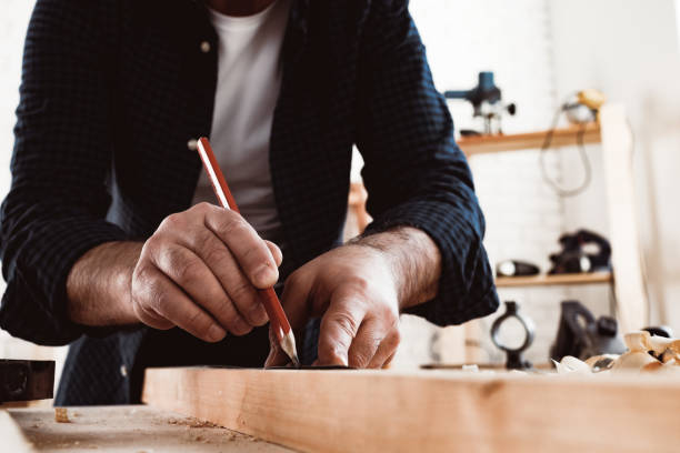 istock Carpenter makes pencil marks on a wood plank 1304873897
