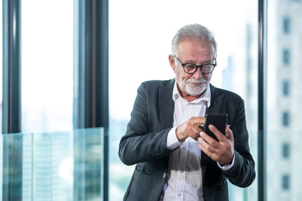 istock Senior businessman using smart phone communication him work.  People retire check data stock market on smartphone for investment.  City background. Business and Technology Concept. 1304874781