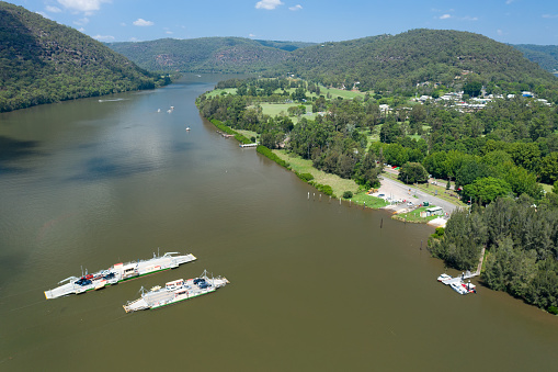 Aerial view of ferries transporting vehicles across the Hawkesbury River at Wisemans Ferry, NSW, Australia.