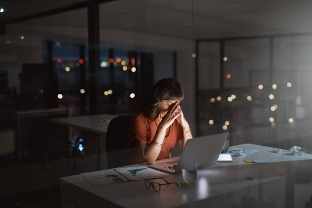 I'm no where close to finishing this deadline tonight Shot of a young businesswoman looking stressed out while working on a laptop in an office at night burnout stock pictures, royalty-free photos & images