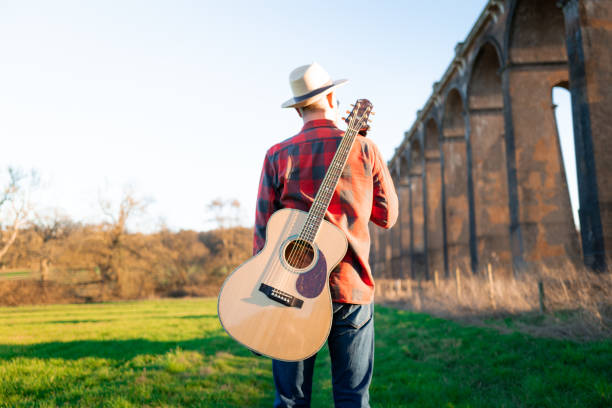 istock Man wandering in nature at sunset with guitar on his back 1304879070