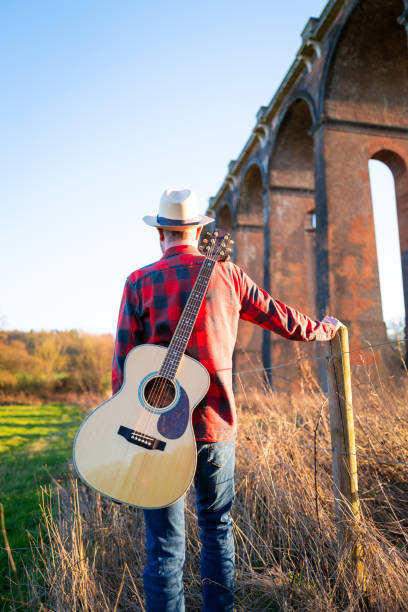 istock Man wandering in nature at sunset with guitar on his back 1304879071