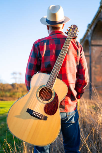 istock Man wandering in nature at sunset with guitar on his back 1304879073