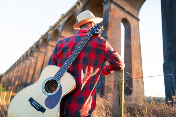istock Man wandering in nature at sunset with guitar on his back 1304879089