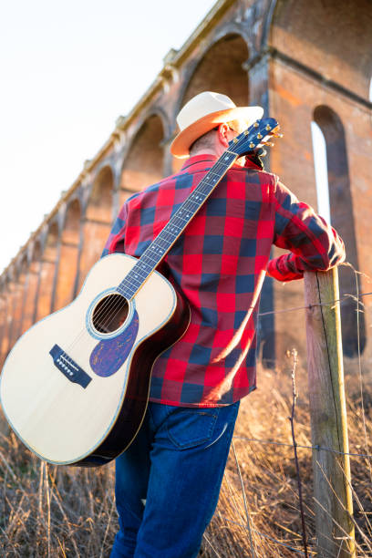 istock Man wandering in nature at sunset with guitar on his back 1304879090