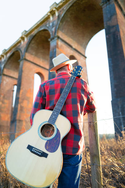 istock Man wandering in nature at sunset with guitar on his back 1304879107