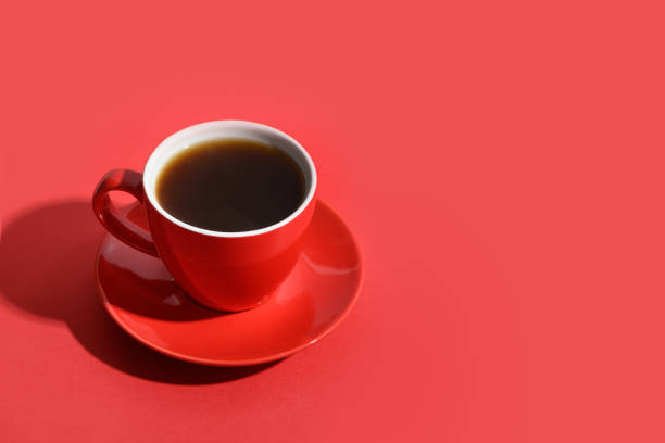 istock Red cup of coffee and beans on red background. Copy space 1304879722