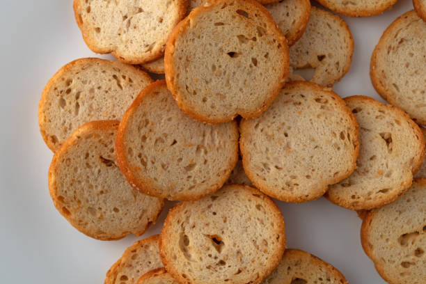 Overhead view of sesame round melba toast on a white plate.