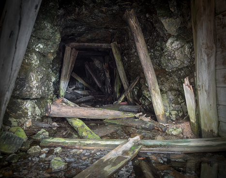 Abandoned mine interior. Dark underground tunnel with rotten wooden supports