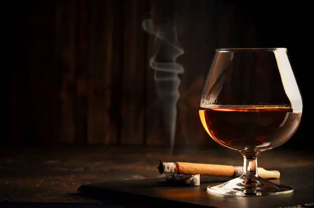 Rum in glasses with a bottle of rum and a cigar in the background. Black background