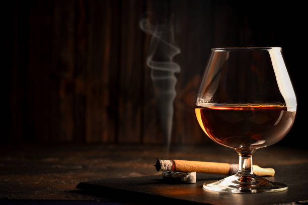 rum in glasses with a bottle of rum and a cigar in the background. - cigar whisky bar cognac imagens e fotografias de stock