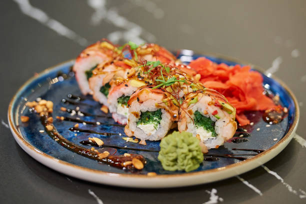 istock Sushi rolls with seaweed, cheese, and shrimps on a blue ceramic plate 1304886161