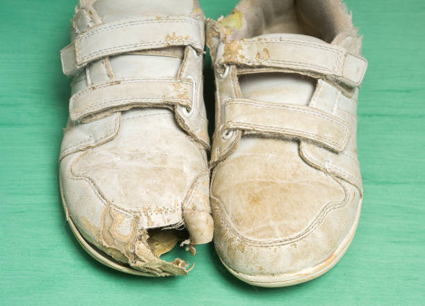 Pair of old worn black sneakers isolated on white background. Clipart of the bad disheveled male shoes close-up