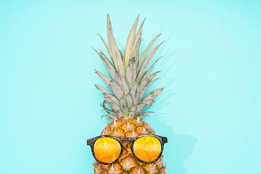 Pineapple on the blue background with yellow sunglasses