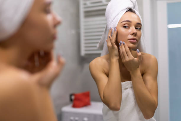 istock Young woman in bathrobe looking in bathroom mirror after shower 1304887652