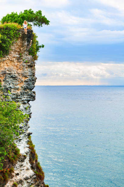 Happy girl have fun on summer beach holiday. Young woman relax at rock cliff above sea. Looking at beautiful view of sunset sky. Healthy family lifestyle, summer travel on tropical island. positivo, chica, feliz, alegre, tener, recreación, fondo, al aire libre, ocio, banner, saludable, estilo de vida, activo, veraniego, escalofriante, alegría, mirada divertida, relajante, ver, puesta de sol, copia, espacio, wisata, visita,
