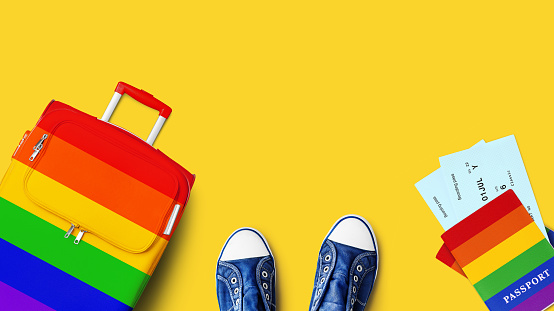 LGBT pride people travel banner, summer holidays, vacation, tourism, LGBTQ community rainbow flag colors suitcase, passport, airplane boarding pass, flight ticket, shoes, yellow background, copy space