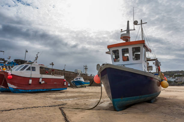 istock Fishing boats beached at low tide in St. Ives' Harbour, Cornwall, UK: rainstorm approaching. 1304893146