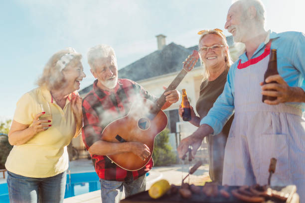 istock Senior friends playing the guitar and singing while having a backyard barbecue party 1304896089