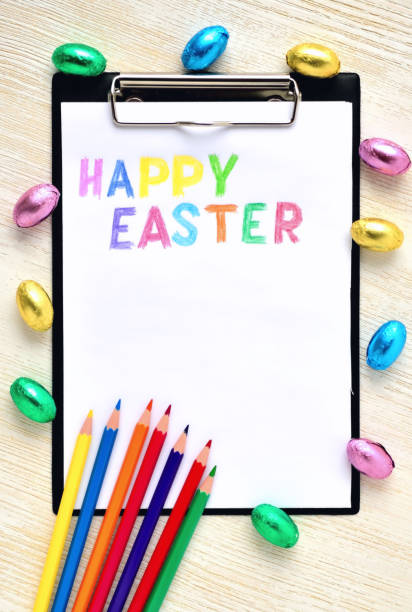 istock The inscription of merry Easter on a white sheet surrounded by small chocolate eggs and colored pencils 1304896577