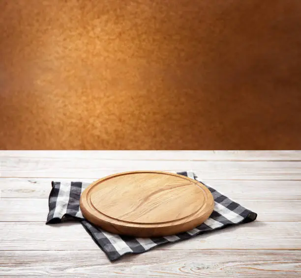 Photo of Napkin and board for pizza on wooden desk. Kitchen background.