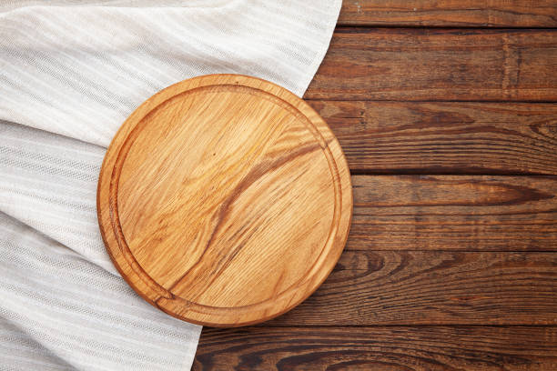 istock Empty pizza board and white napkin on wooden top view. 1304900801