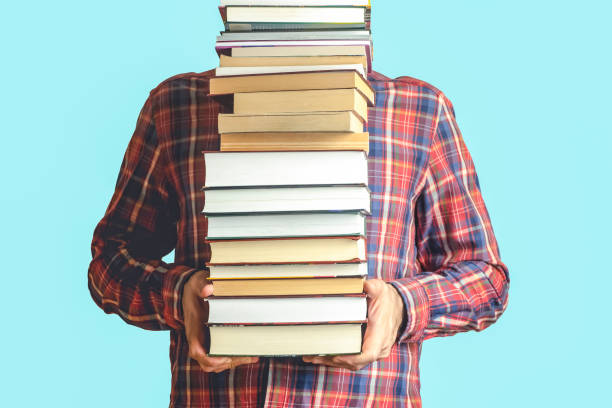 istock Student with books on a blank colored background. Education, reading and study background concept 1304903632
