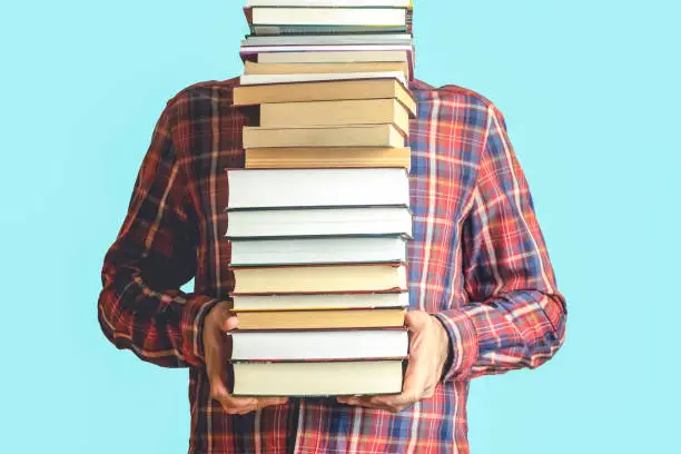 Student with books on a blank colored background. Education, reading and study background concept.