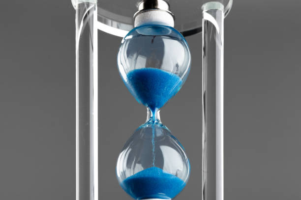 istock Blue hourglass on gray background close up 1304904577