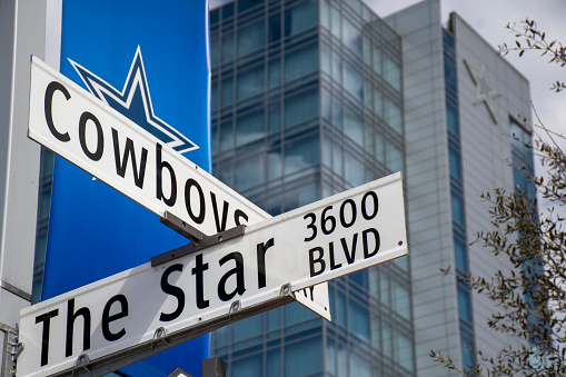 Frisco, Texas, USA - March 01, 2021: Street sign at the intersection of Cowboys Way and The Star, complex of the Dallas Cowboys, Omni Hotel Frisco in Background, no people, sunny day