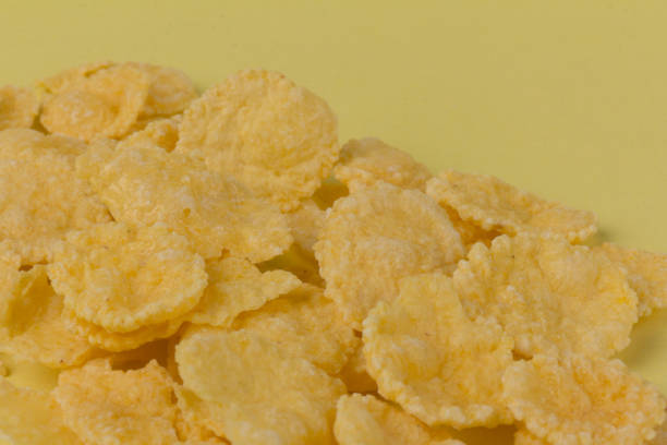 istock Pile of yellow cornflakes on yellow  background 1304905433