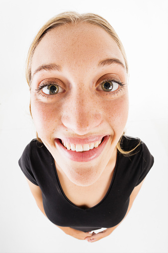 Young woman looking up with a smile, shot with a fisheye lens.