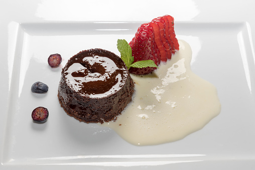 bunet pudding, traditional italian Piedmont dessert in white plate with strawberries and eggnog