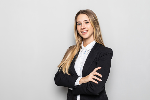 Smiling business woman with crossed arms standing against white background. Isolated.