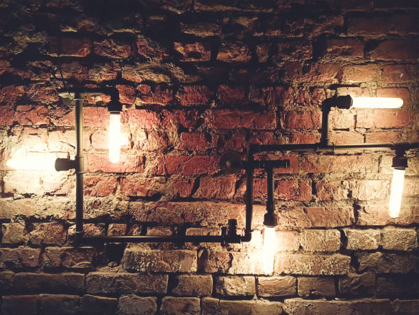 istock Interior design of vintage wall. Rustic design, brick wall with light bulbs and pipes, low lit bar interior 1304910043