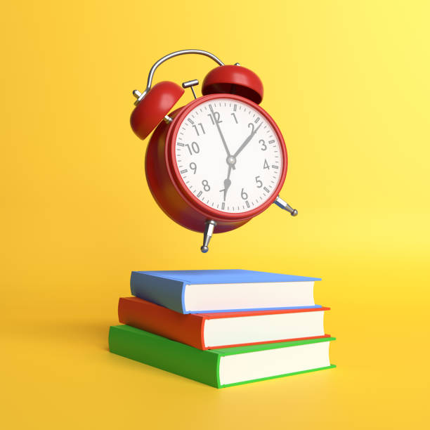 istock Alarm clock and color books on pastel yellow background 1304915230