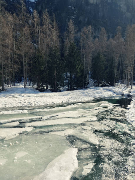Frozen river with ice sheets in winter in Valtellina, Val di Mello, Italy