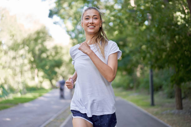 istock Woman running asphalt road summer park 1304918574